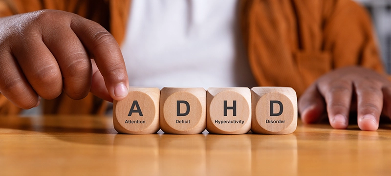 Close up of a boy's hands assembling the letters "ADHD," with corresponding words below each block to spell out "Attention Deficit Hyperactivity Disorder."